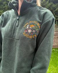 Forest green embroidered quarter zip fleece featuring The Autumn Society autumn design with books, candle, mug and autumn leaves on the chest.