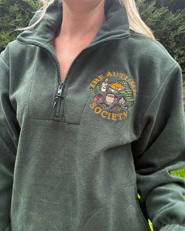 Forest green embroidered quarter zip fleece featuring The Autumn Society autumn design with books, candle, mug and autumn leaves on the chest.